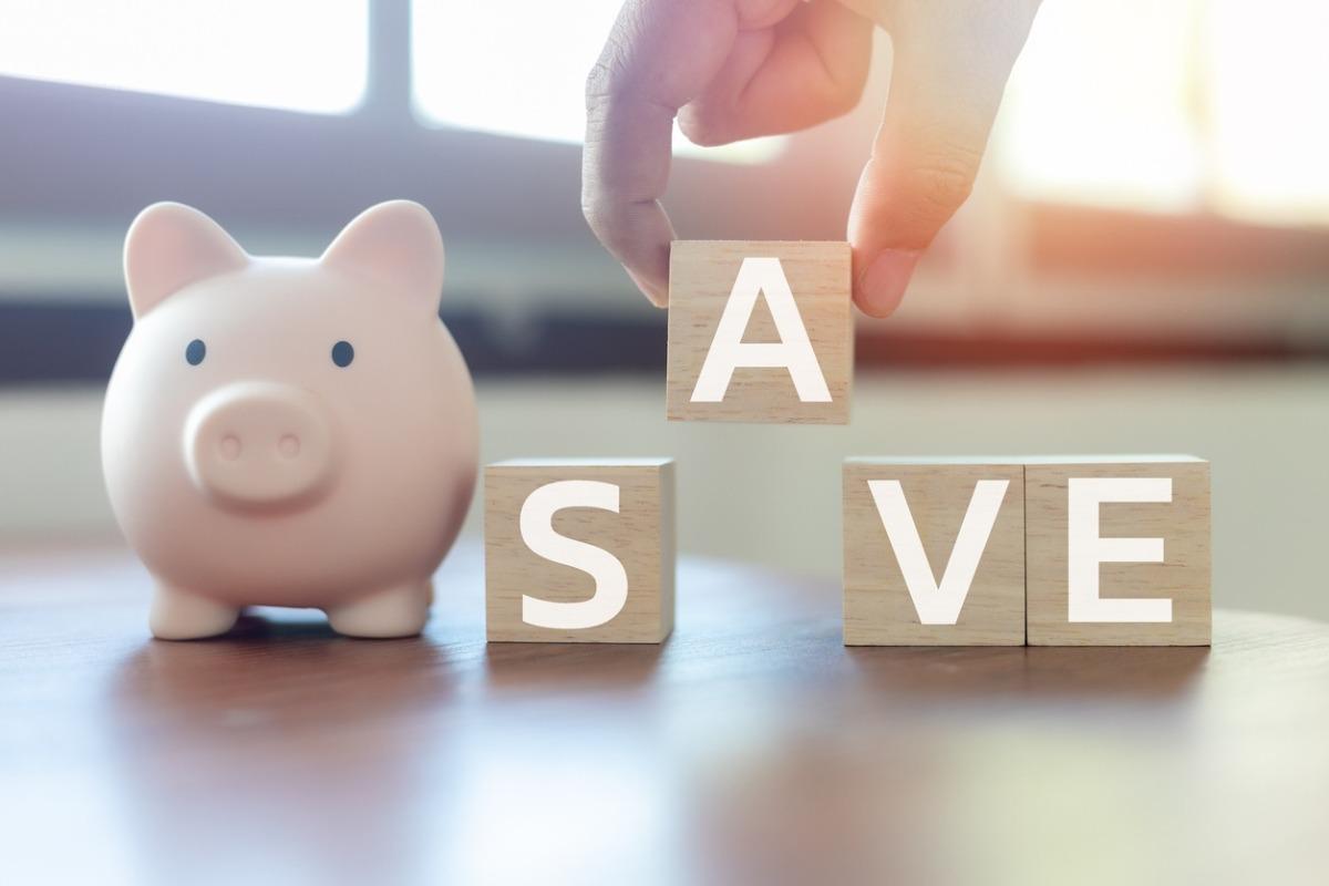 Piggy bank beside wooden blocks spelling 