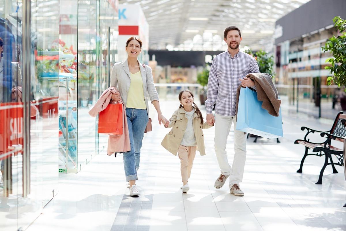 Happy family of shoppers enjoying leisure in large modern trade center on weekend