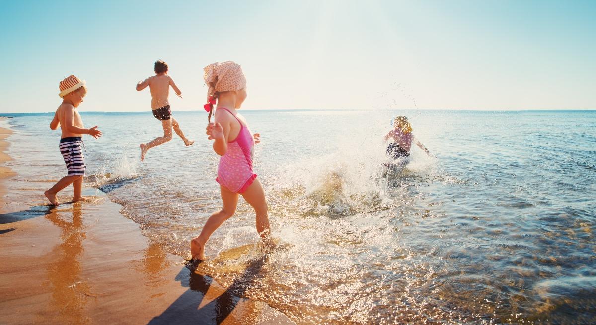 children running into the waves at beach